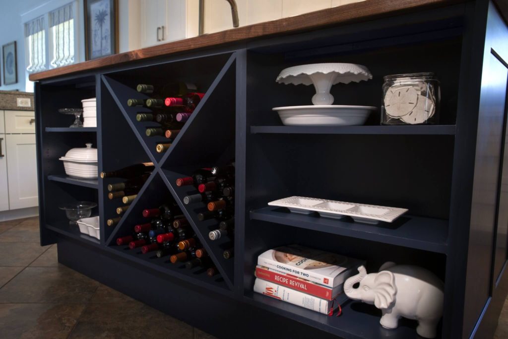 Kitchen island side view with wine storage and decorative items on a shelf.