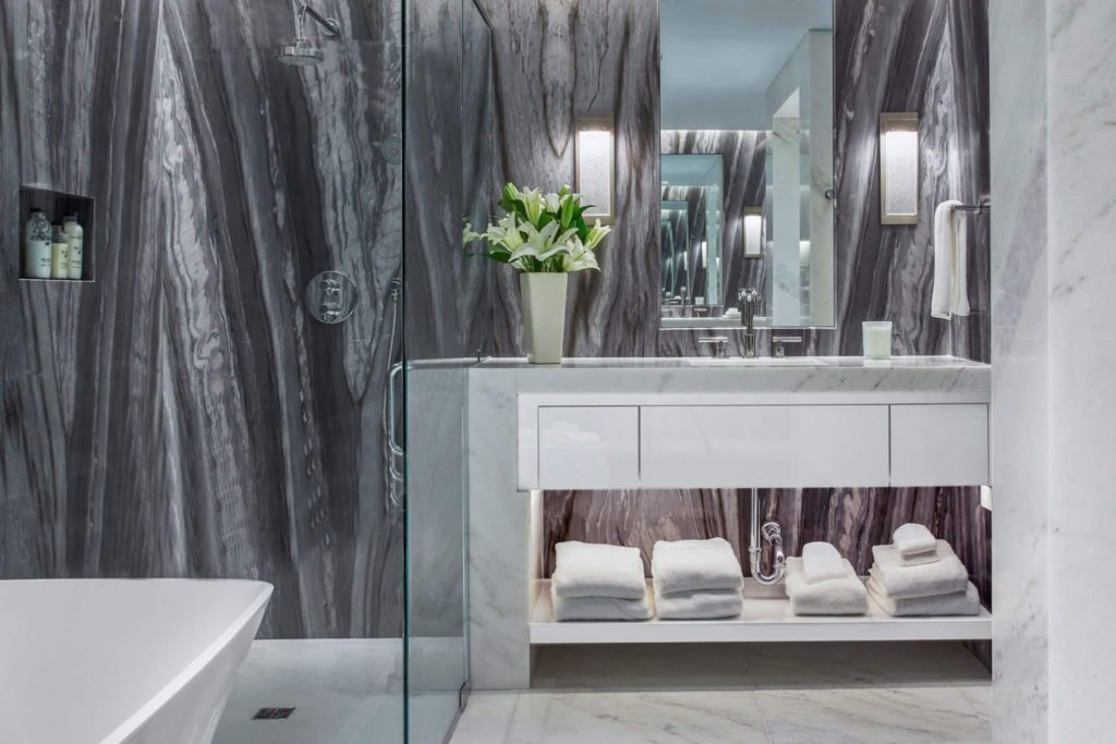 Contemporary bathroom vanity with open shelving and a glass door to a white tub on the side.