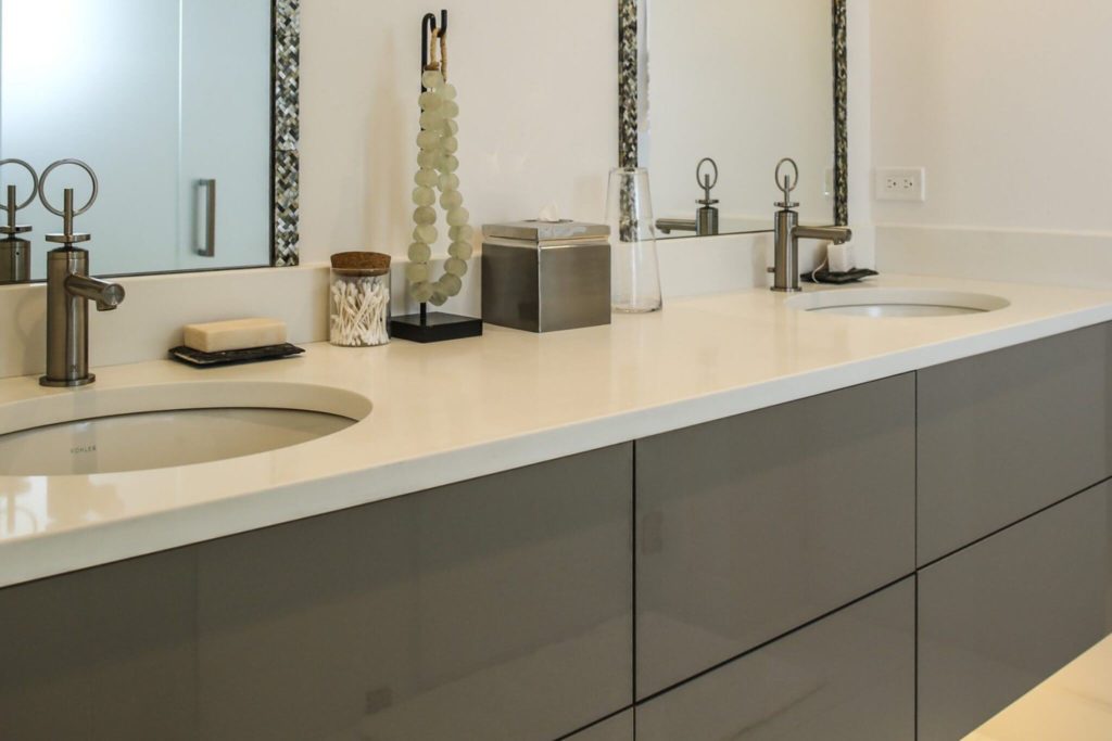 Sleek, modern bathroom vanity with ivory countertop and double sinks with mirror overtop