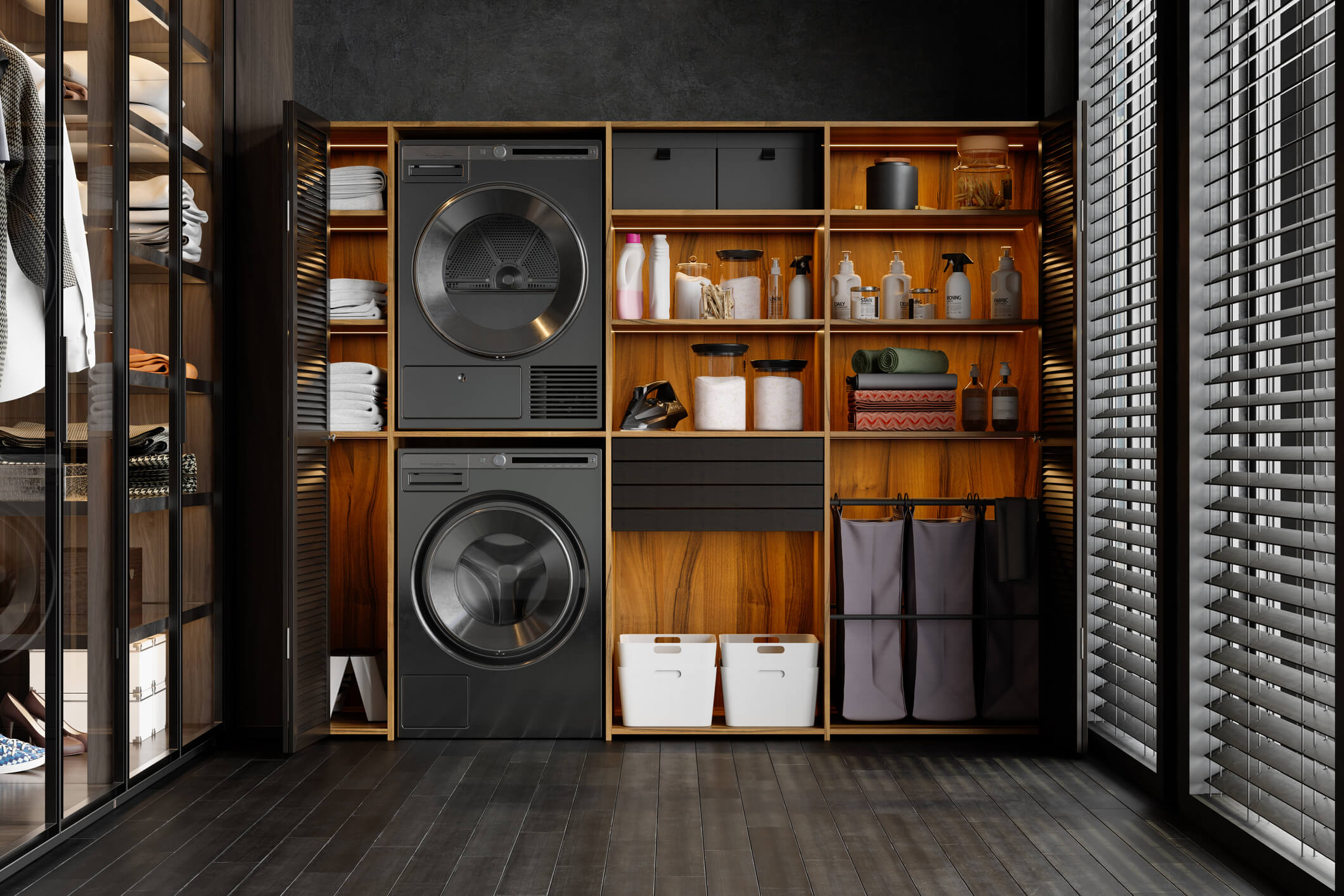 Modern laundry room with a stacked, black washer and dryer and open shelving with laundry supplies. Slat blinds on the windows and wood flooring.